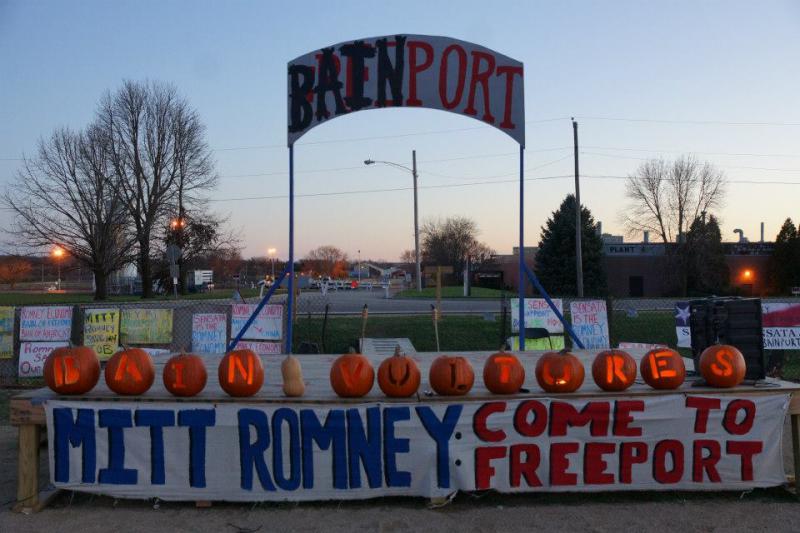 image of the stage at bainport with pumpkins that spell out "bain vultures" and sign that says "Mitt Romney: Come to Freeport"