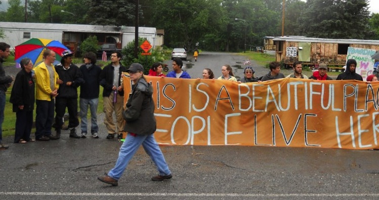 Protesters hold a sign that reads "This is a beautiful place, people live here"