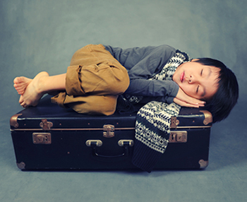 Child sleeping on suitcase (Source: Shutterstock)