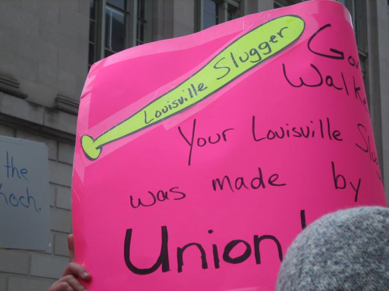 This sign, held by a protester at the rally, depicts a Louisville Slugger baseball bat and reads, 'Governor Walker: Your Louisville Slugger was made by a Union Worker!' Walker made a reference to having a Slugger in his office after the fake 'Koch' prank caller, Buffalo Beast editor Ian Murphy, indicated Walker should 'bring a baseball bat' to a conversation with Democratic Senators when they return to the state.
