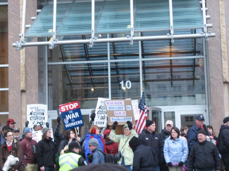 Protesters clamor around the doorway of 10 E. Doty St.