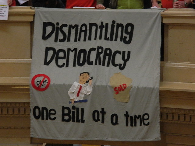A banner in the capitol "dismantling democracy one bill at a time