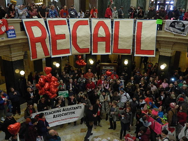 A crowd in the rotunda, with a large RECALL banner.