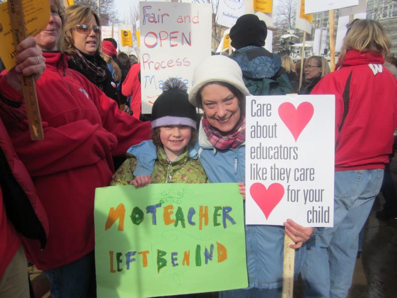 School was canceled today in Madison and many other Wisconsin communities. Seven-year-old Whitman holds a sign "No Teacher Left Behind" and stands with her Kindergarden teacher Mary Jo Yttri of Lapham Elementary School.